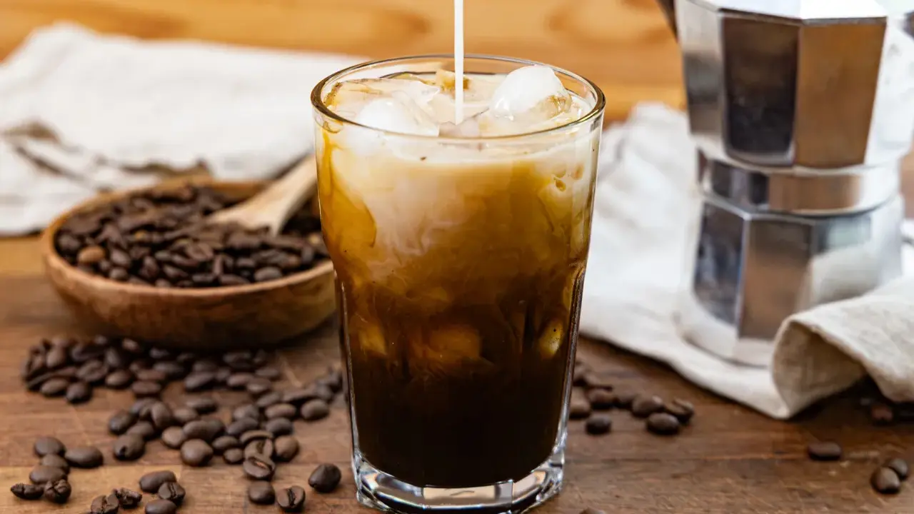 Ein Glas Eiskaffee mit Milch, Eiswürfeln und Kaffeebohnen. Perfekt für dein Cold Brew Rezept.
