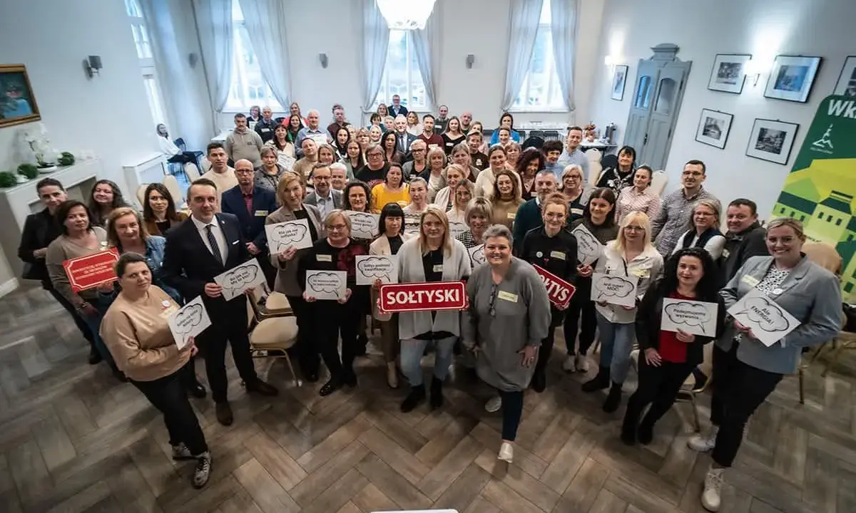 Grupa osób trzyma tabliczki z napisami, m.in. "SOŁTYSKI", "Podnosimy wyzwania", "Ale ENERGIA!".