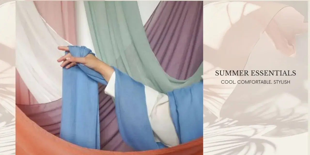 A hand drapes light blue fabric, suggesting the best clothing material for summer is breathable and cool.