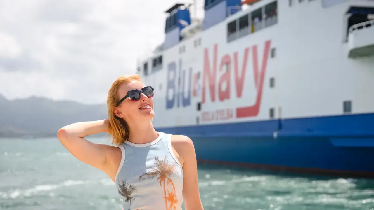 Femme souriante devant le **récepteur blu** et blanc du navire "Blu & Navy".