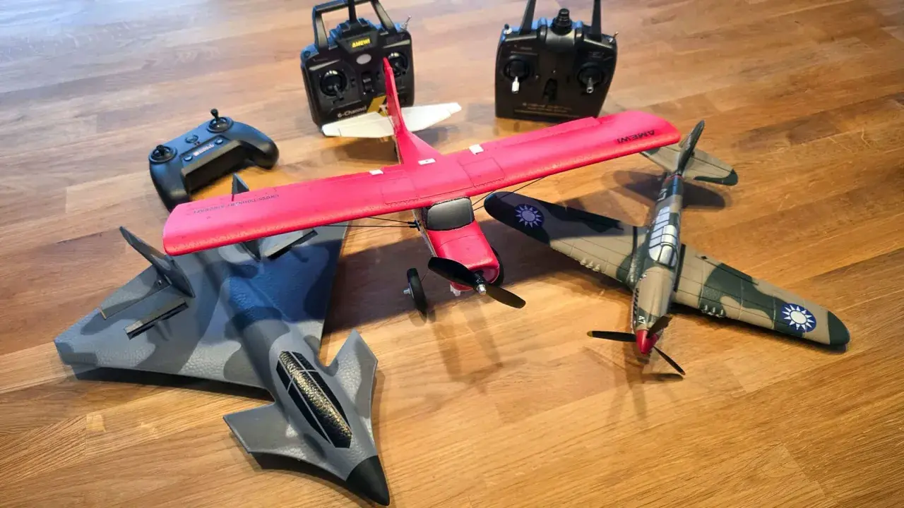 Mehrere ferngesteuerte Flugzeuge, darunter ein rotes Kunstflugmodell und ein Tarnkappenbomber, liegen bereit, um abzuheben.