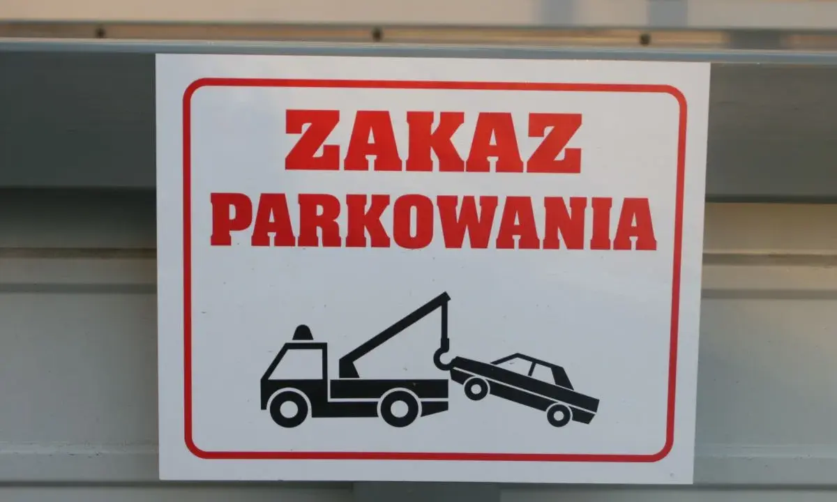 Zasady parkowania na parkingu: zakaz parkowania, holowanie pojazdów. Znak ostrzega przed odholowaniem źle zaparkowanego auta.