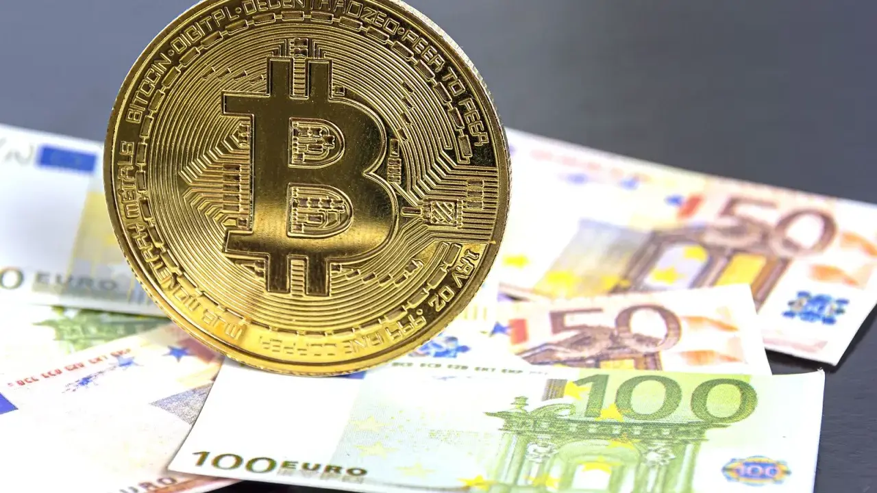 Moneda de Bitcoin sobre billetes de euro. El futuro del euro digital podría ser así.