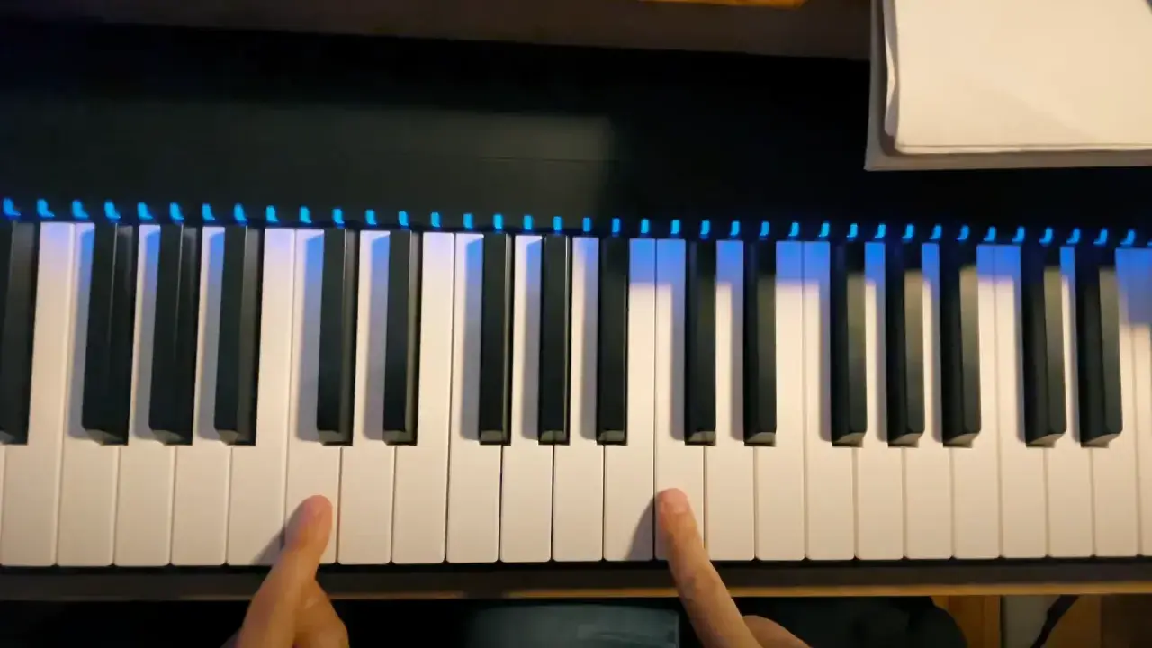Deux doigts prêts à jouer un accord sur un piano numérique avec des lumières bleues illuminant les touches.
