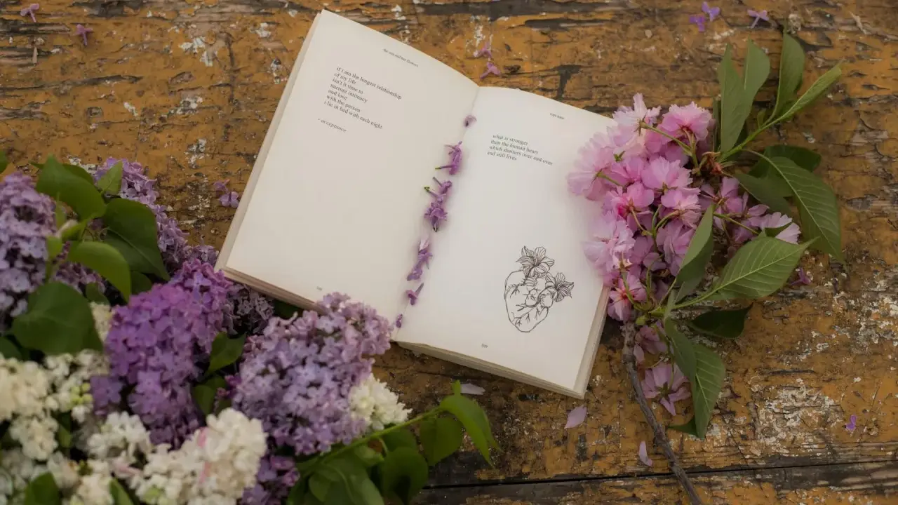 Un libro aperto con poesie d'amore passionali anonime, decorato con fiori lilla e rosa su un tavolo di legno consumato.