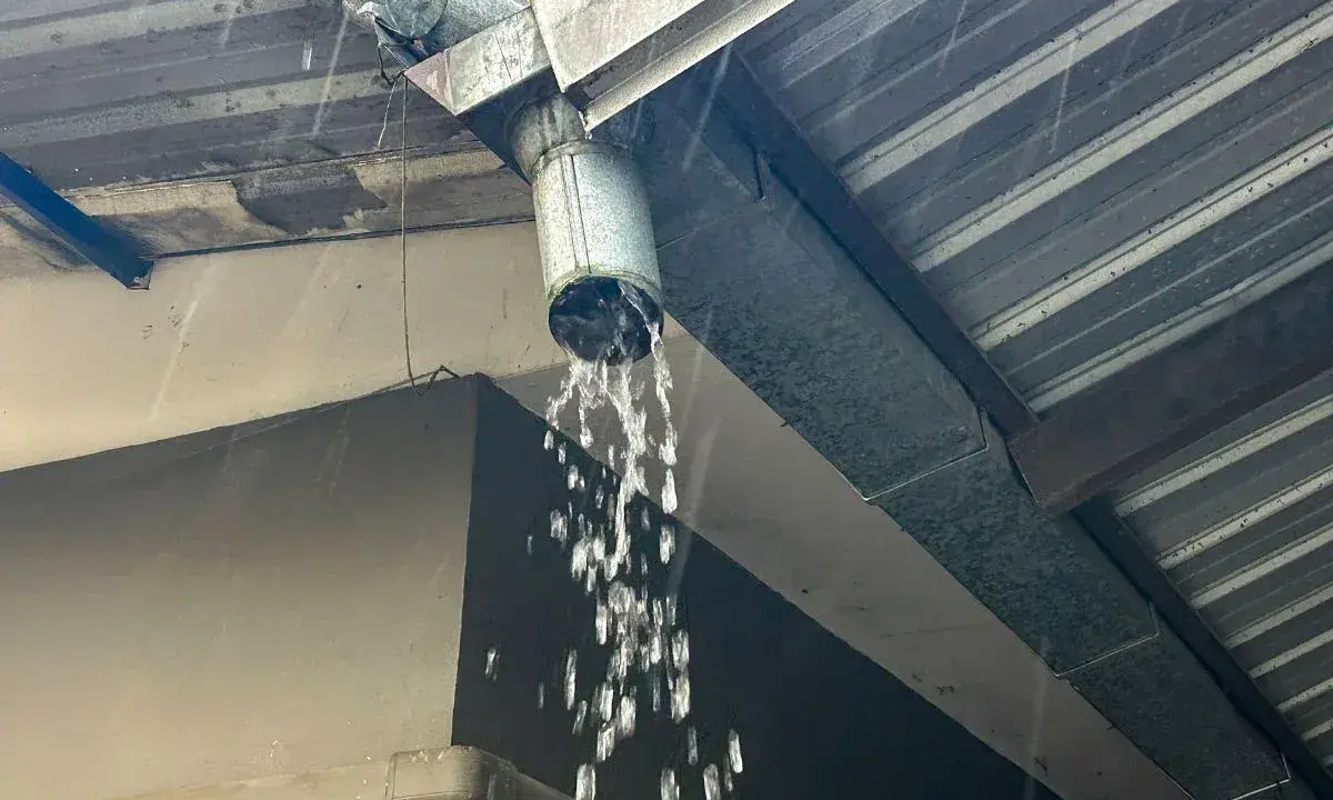 Gouttière en métal sous une pluie battante, l'eau s'écoule abondamment du tuyau, assurant l'évacuation eau de pluie.