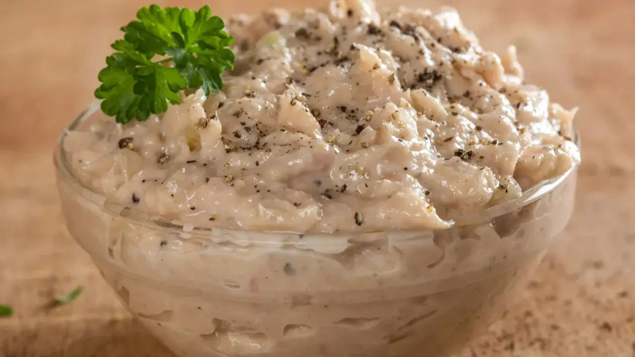 Pyszna pasta z tuńczyka w szklanej miseczce, posypana pieprzem i udekorowana natką pietruszki. Idealna na kanapki.