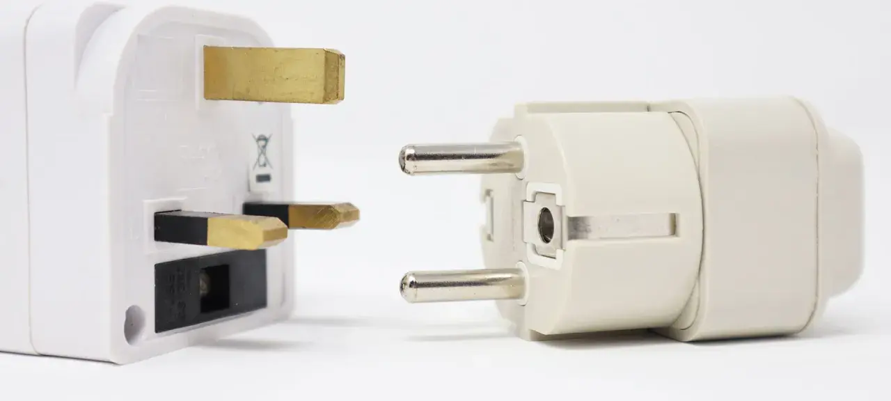 Reiseadapter für den Strom in Spanien. Ein britischer Stecker trifft auf einen europäischen Stecker.