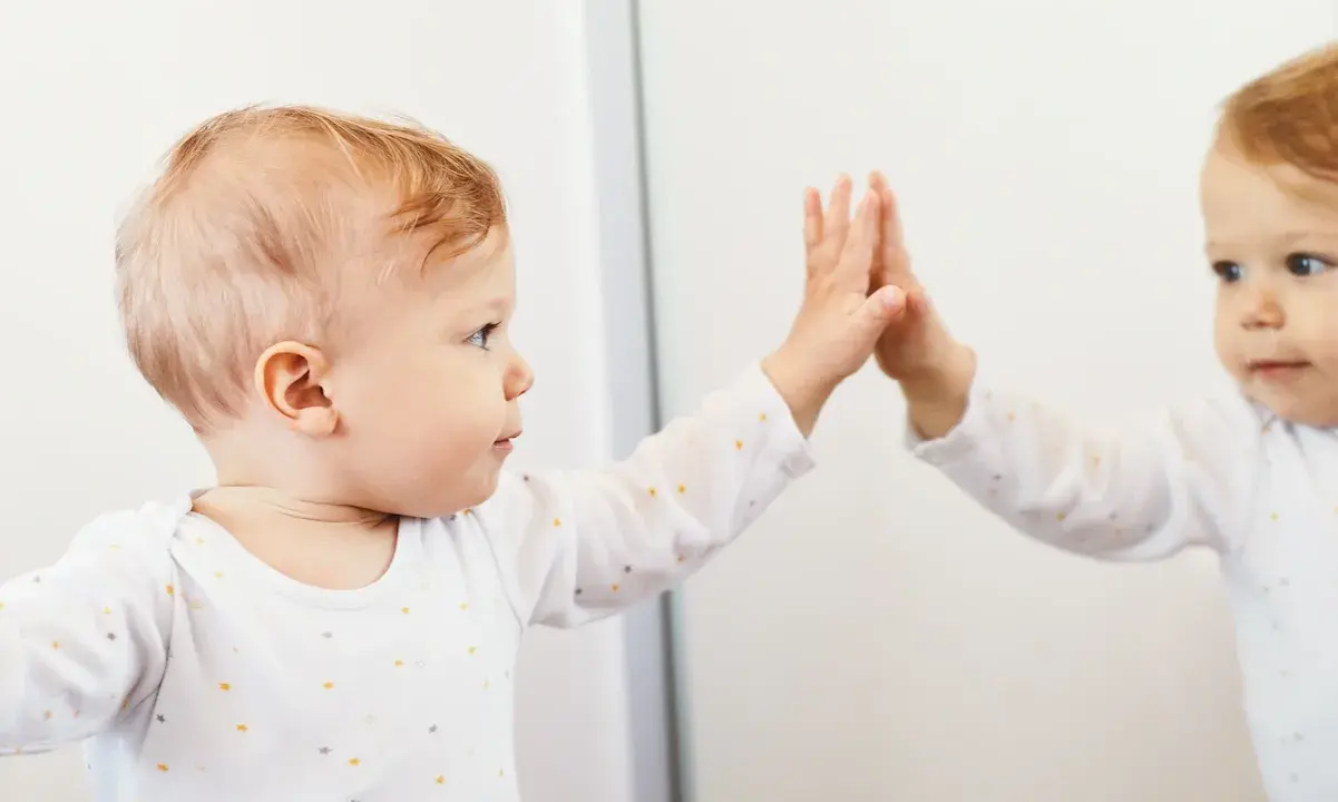 Bambino che tocca il suo riflesso, un momento chiave nella costruzione del sé nel bambino.