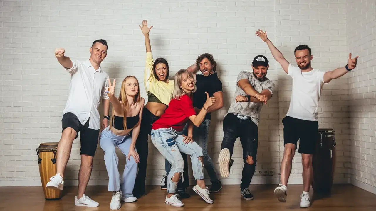Grupa ludzi wesoło pozuje, gotowa do tańca zouk.