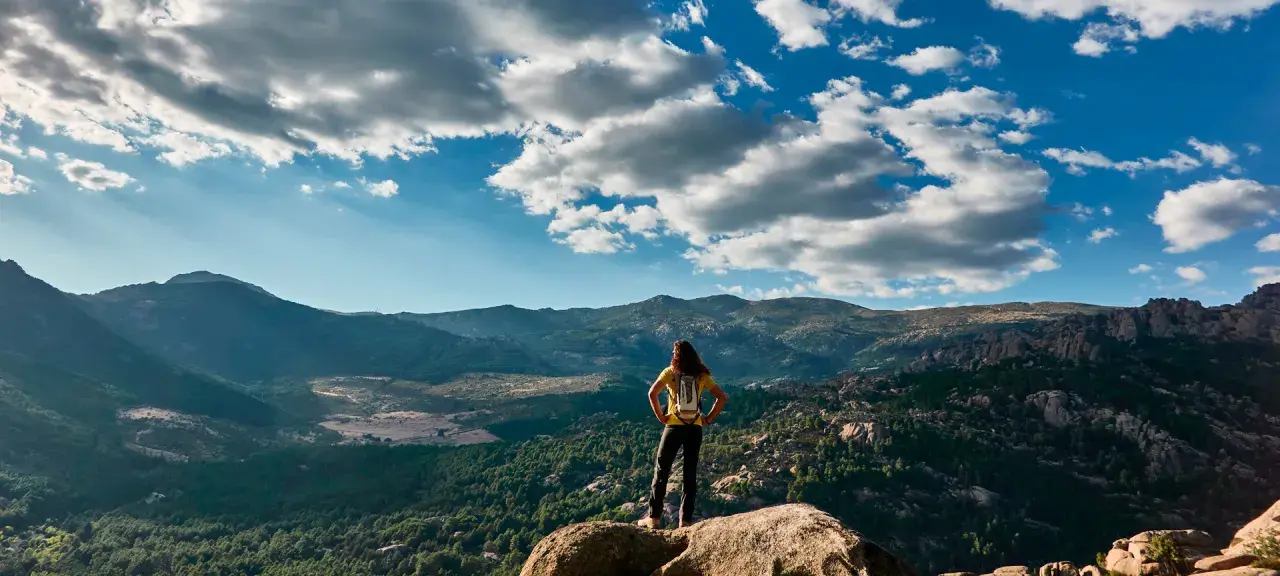 Wanderin auf einem Felsvorsprung mit Blick auf die Berge, ein perfekter tagesausflug madrid.