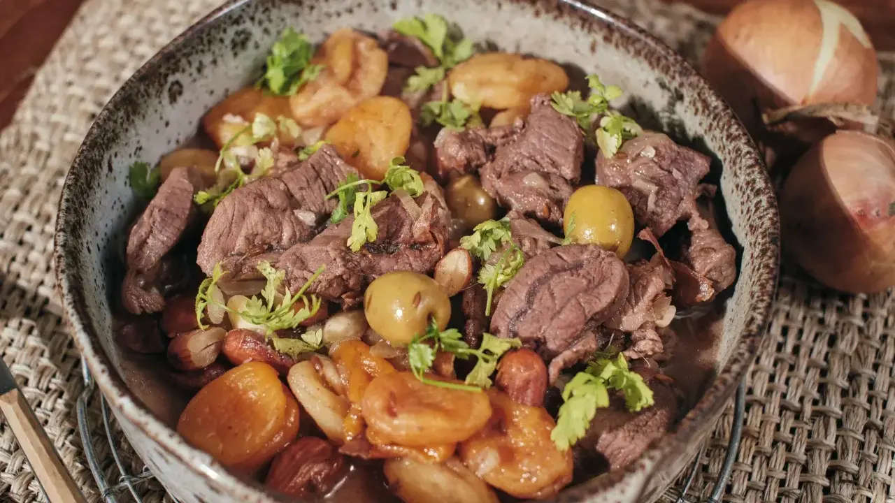 Un savoureux tajine de chevreuil mijoté avec des pommes de terre et des olives, garni de coriandre fraîche.