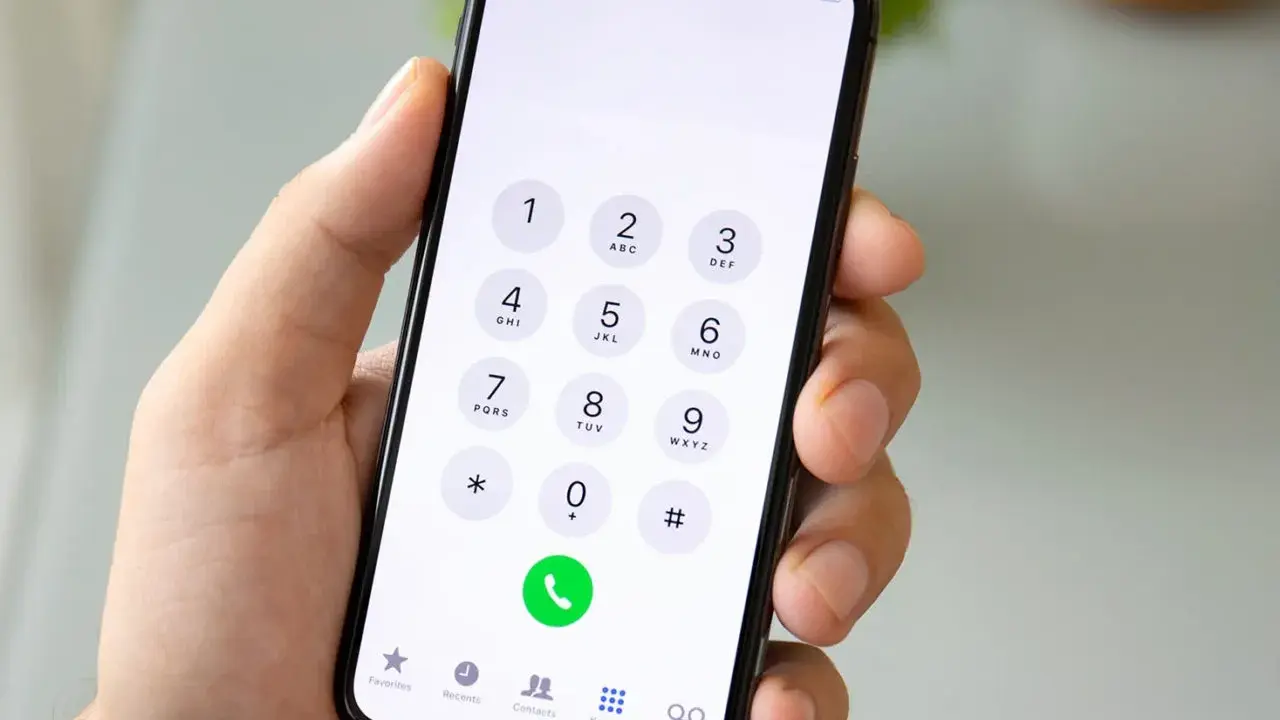 Dłoń trzyma smartfon z klawiaturą numeryczną. Chcesz wiedzieć, jak sprawdzić numer? Wpisz go na klawiaturze telefonu.