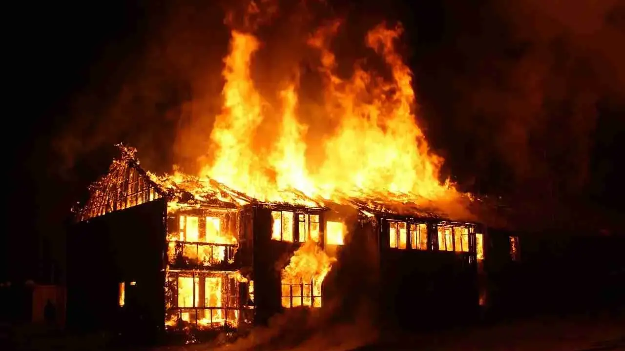 Une maison à deux étages est dévorée par les flammes, le toit s'effondre. L'incendie cause une destruction massive.