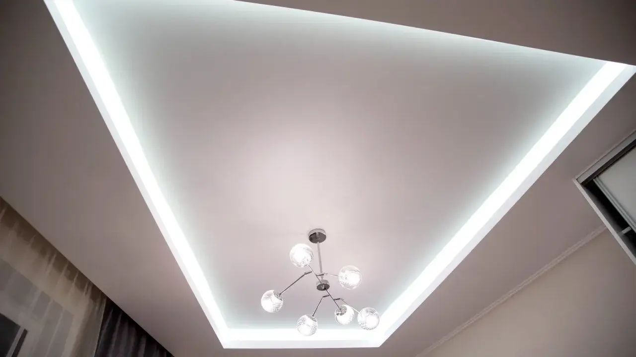 Nowoczesny sufit napinany lustrzany z podświetleniem LED i designerską lampą.