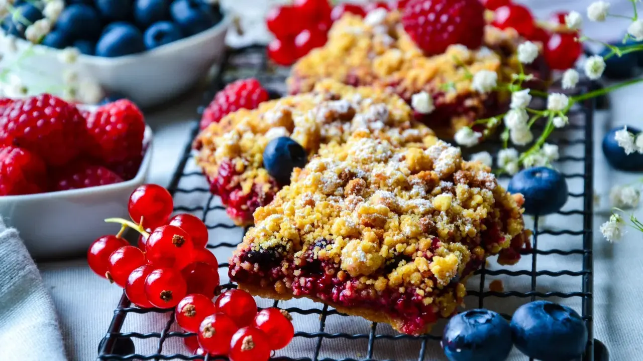 Délicieux crumble aux fruits rouges, garni de framboises, myrtilles et groseilles, saupoudré de sucre glace.