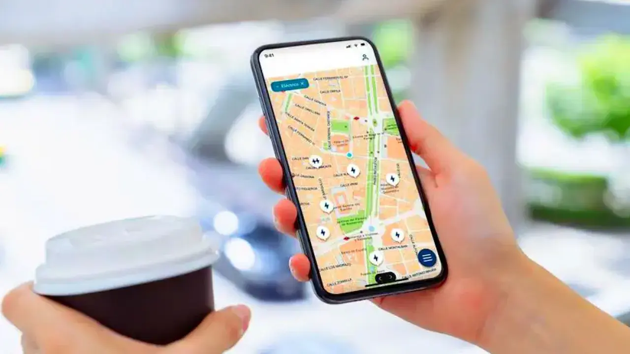 Persona usa un app cargadores eléctricos en su móvil para encontrar puntos de recarga en un mapa.