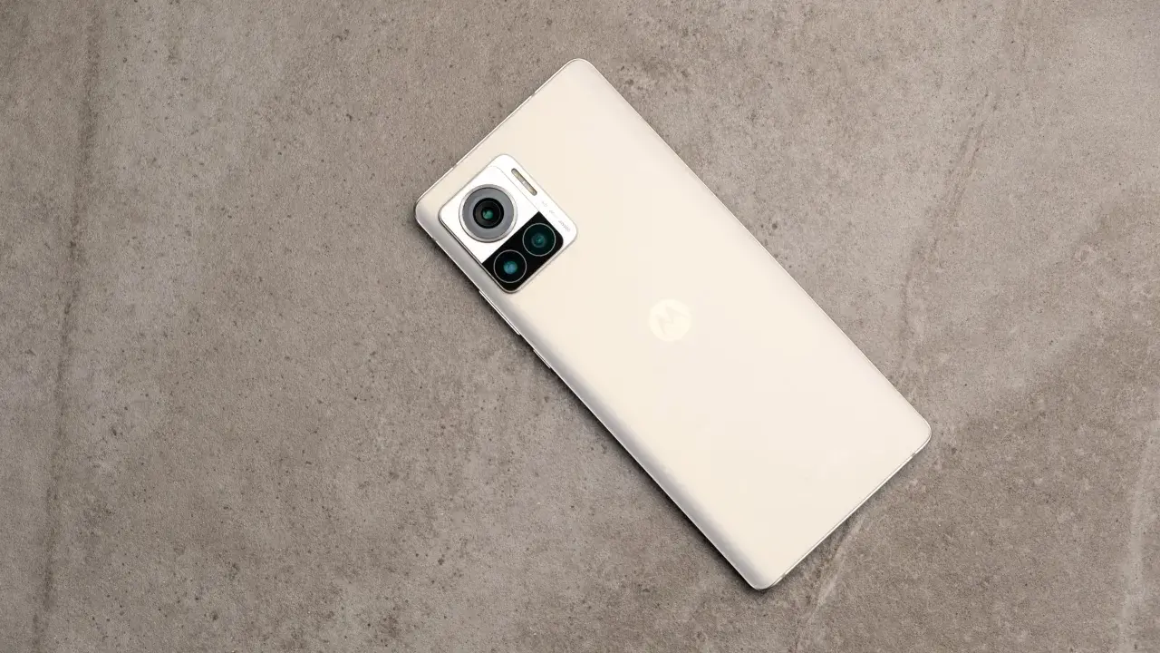 Jasny telefon Motorola edge 30 ultra z potrójnym aparatem na szarym, kamiennym tle.