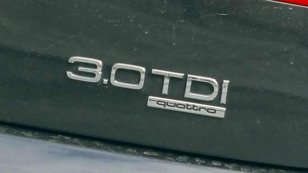 Emblemat "3.0 TDI quattro" na ciemnym lakierze samochodu. Informuje o pojemności silnika 3.0 litra i napędzie quattro.