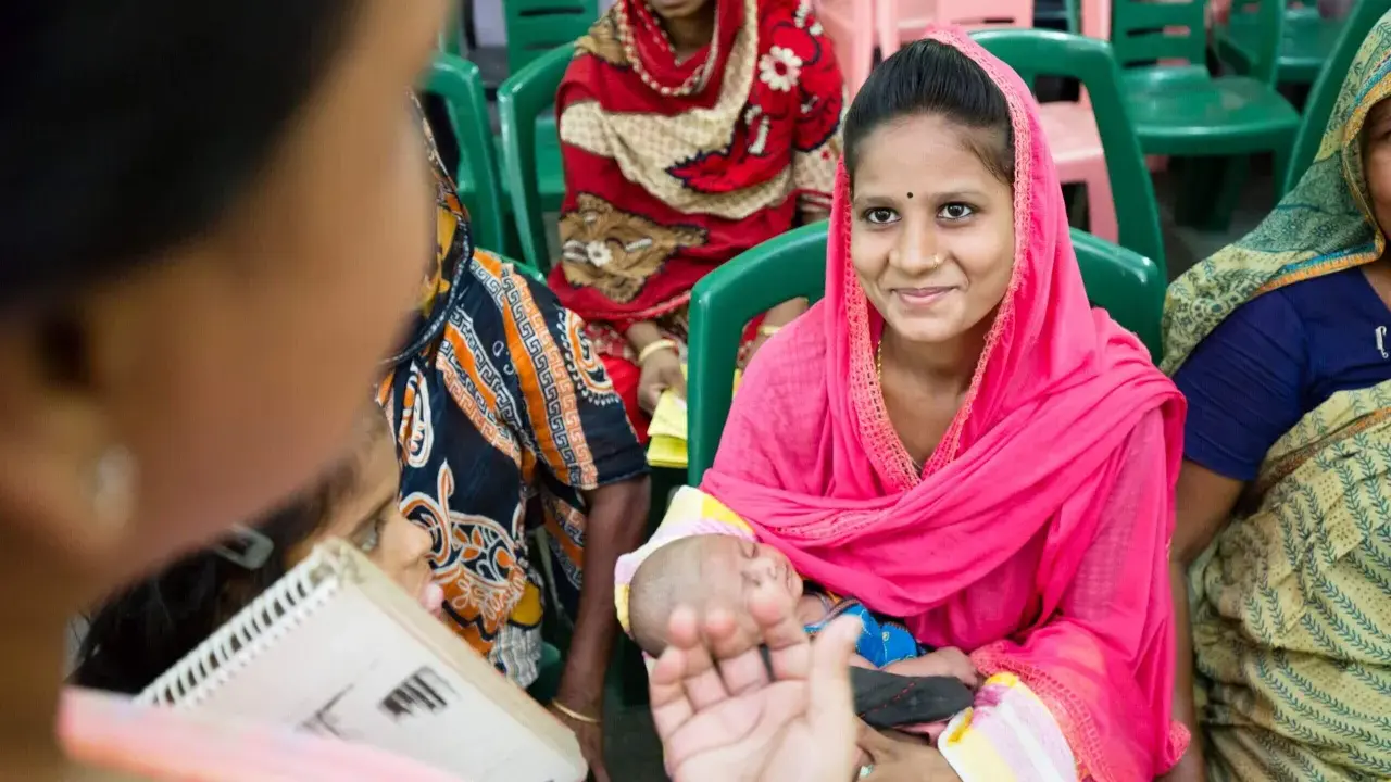 Frauen in bunten Saris, eine hält ein Baby. Sie sitzen auf Stühlen und hören zu. Wann ist sadaka ne zaman verilir?