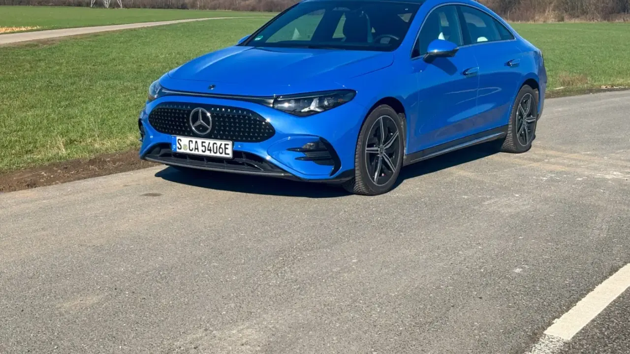 Blauer Mercedes-Benz CLA 250+ EQ auf einer Straße, mit grünen Feldern und einem Strommast im Hintergrund.