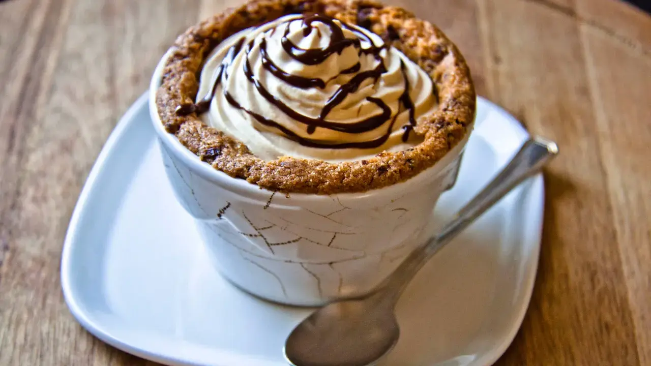 Un délicieux dessert dans une tasse en cookies, garni de crème fouettée et de sauce au chocolat.
