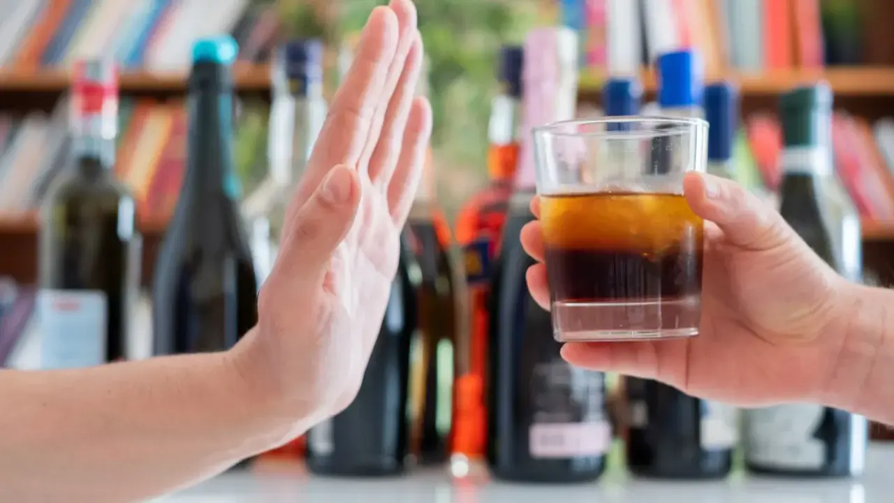 Dłoń odrzuca szklankę z alkoholem, symbolizując początek leczenia alkoholizmu.