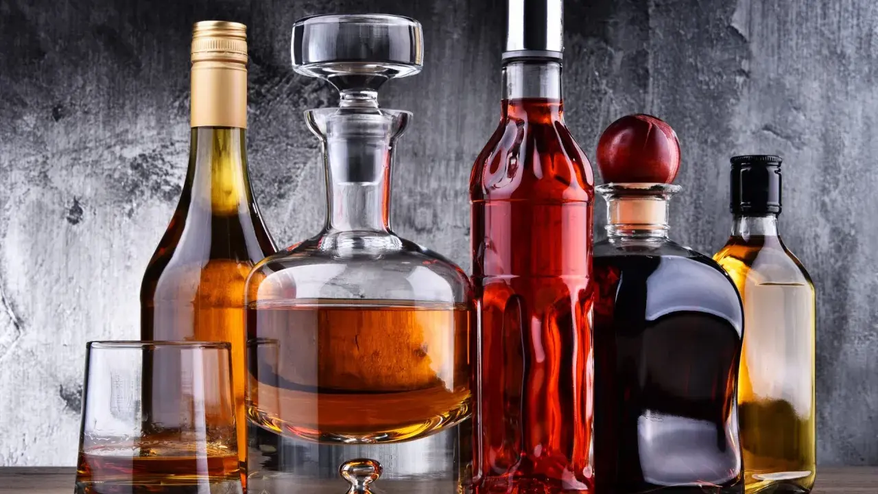 Karafka z koniakiem i inne butelki z brandy na drewnianym blacie.