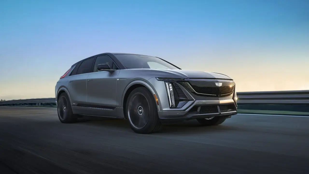 Cadillac Lyriq, un SUV eléctrico que representa el futuro de las marcas americanas de coches, avanza por una carretera al atardecer.