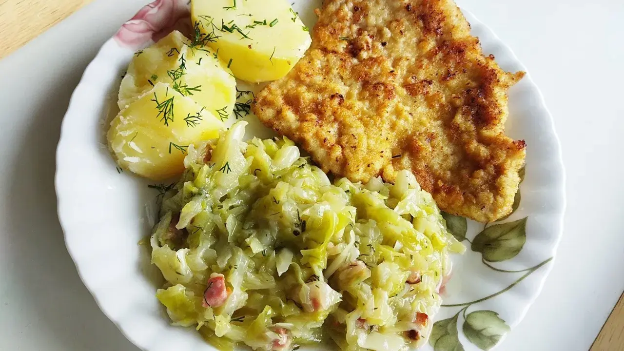 Kotlet schabowy z ziemniakami i młodą kapustą zasmażaną z boczkiem.
