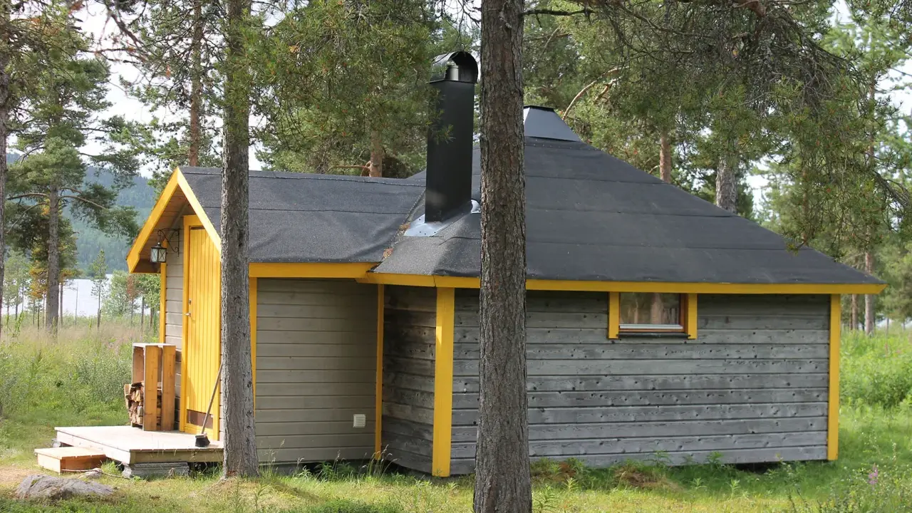 En mysig stuga för camping i Kiruna, omgiven av skog och med en sjö i bakgrunden.
