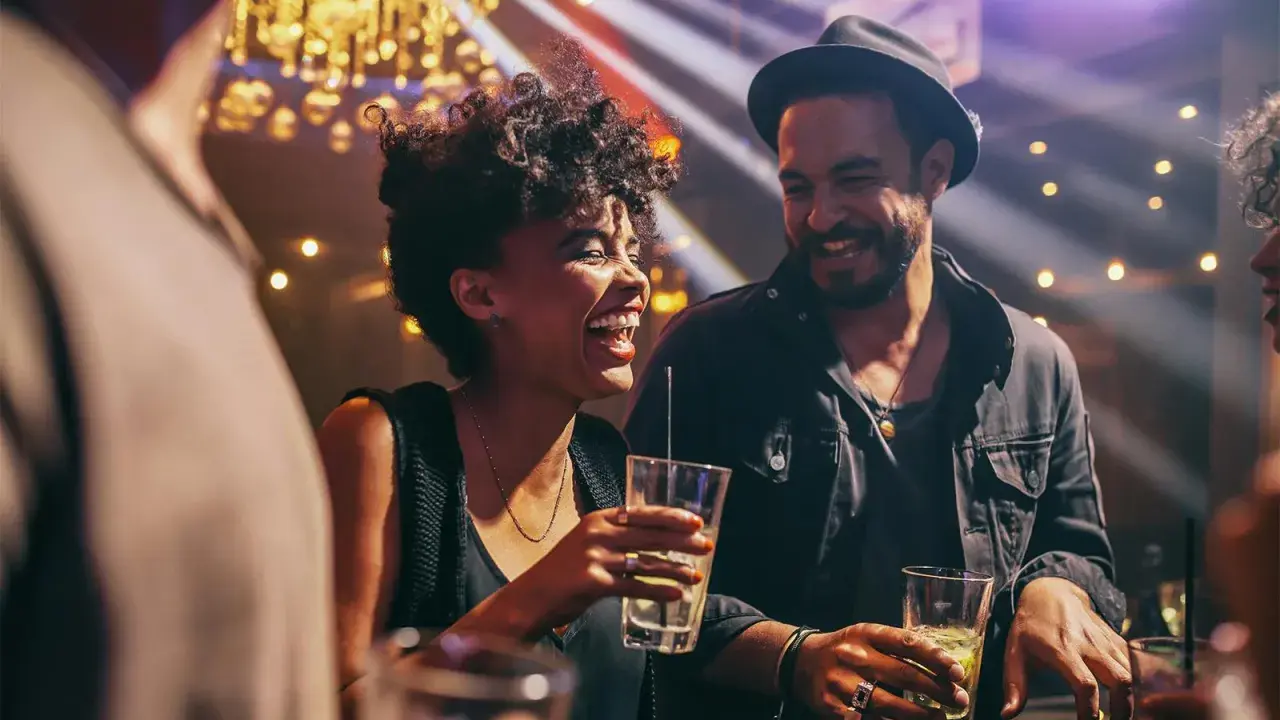Coppia felice ride e beve in un locale notturno di Barcellona, tra luci soffuse e musica.