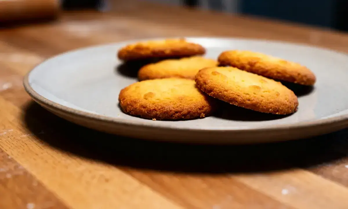 Assiette de sablés fondants au beurre, dorés et appétissants, sur un fond en bois.