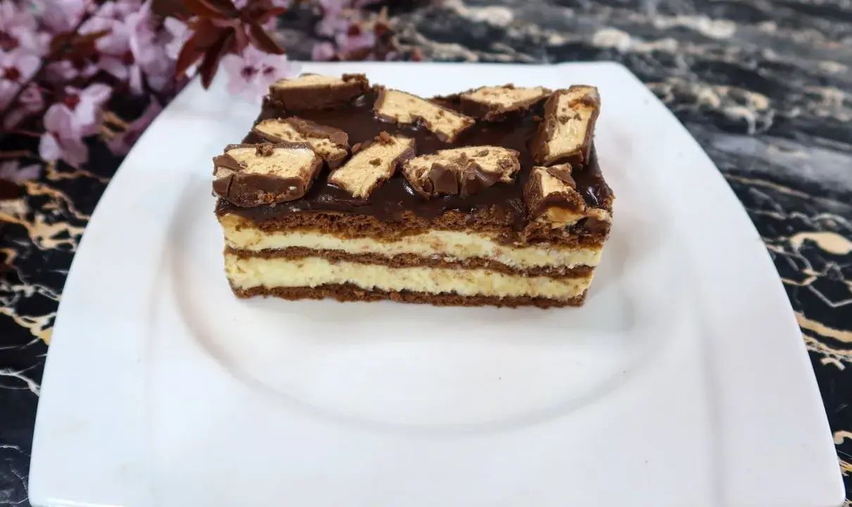 Sernik Milky Way z warstwami kremu i czekolady, ozdobiony kawałkami batoników.