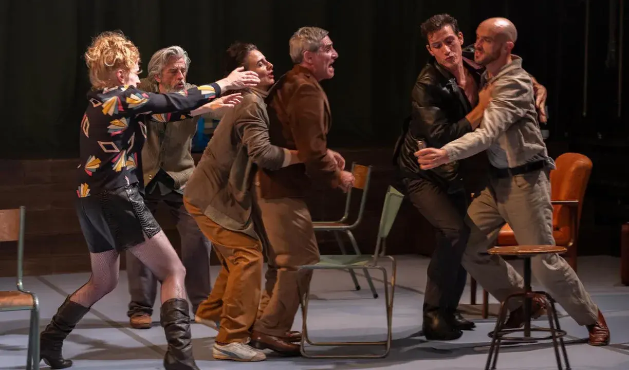 Scène de théâtre tendue. Des hommes se disputent, leurs gestes évoquent une lutte. La scène rappelle la conjugaison du verbe "aboyer" dans un moment de tension.