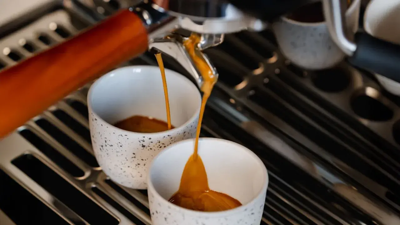 Frisch gebrühter Espresso fließt in zwei Tassen. Hoffentlich schmeckt er nicht zu sauer.