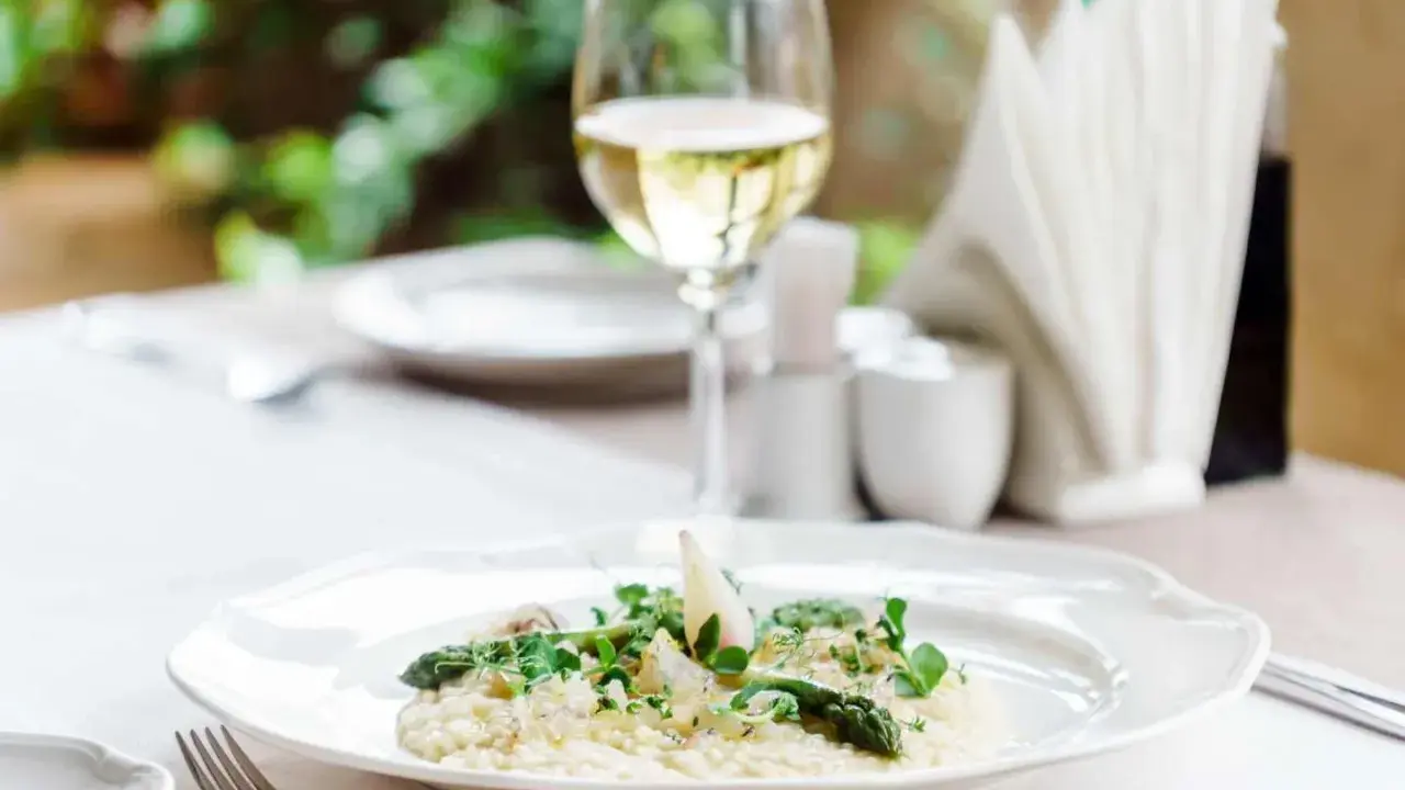 En krämig risotto med sparris och örter, perfekt ackompanjerad av ett glas vitt vin till risotto.