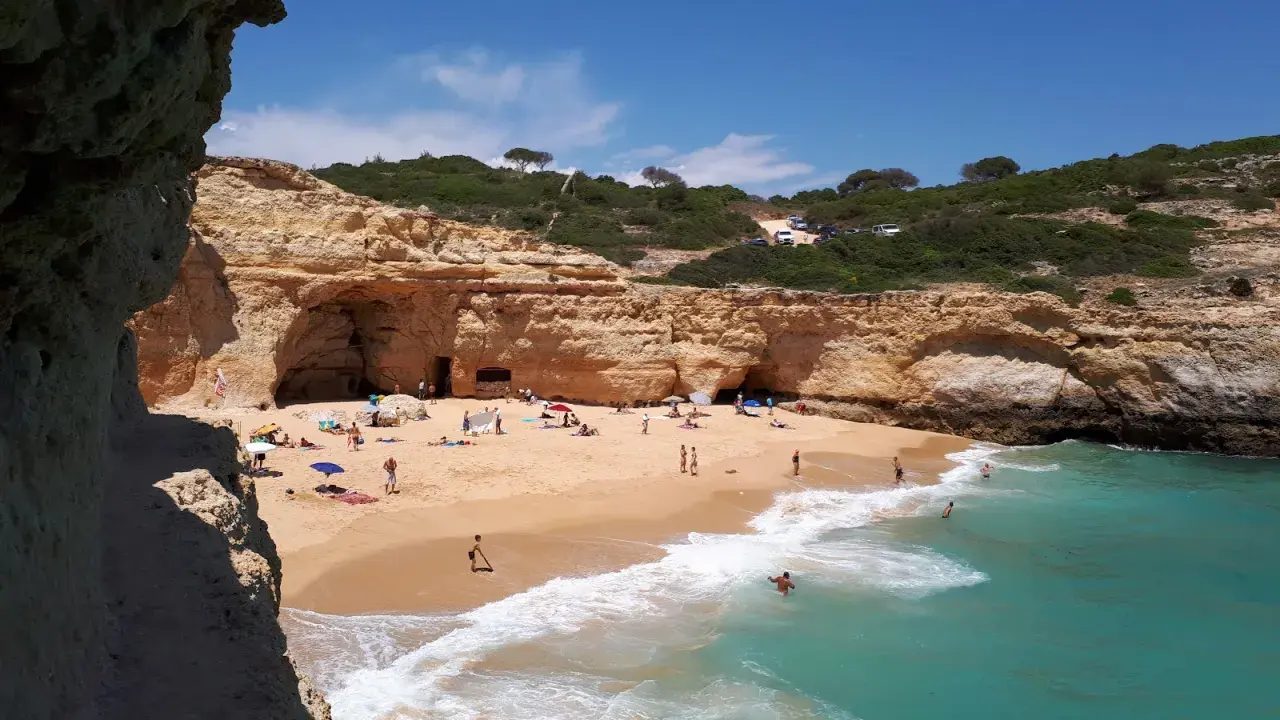 Sonniger Strand an der Algarve, ein echter Geheimtipp mit Felsformationen und türkisfarbenem Wasser. Menschen entspannen sich am Sandstrand.