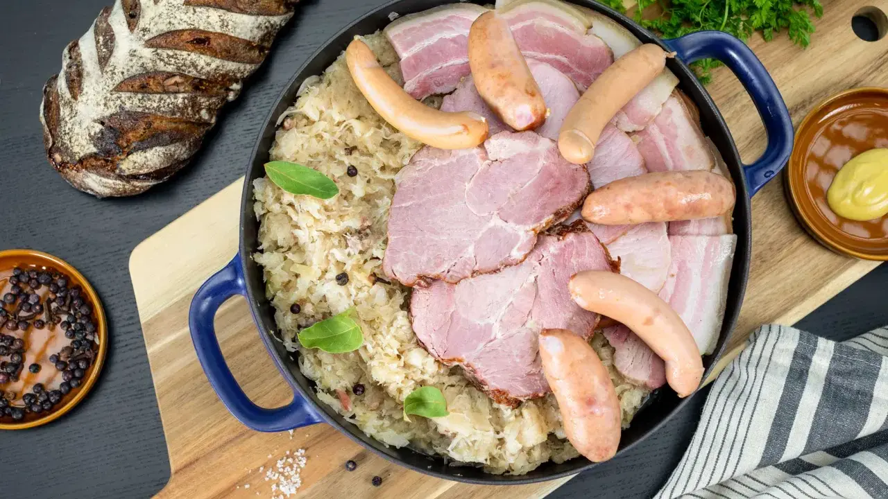 Un plat généreux de choucroute de Noël, garni de saucisses, jambon et lard, accompagné d'une miche de pain rustique.