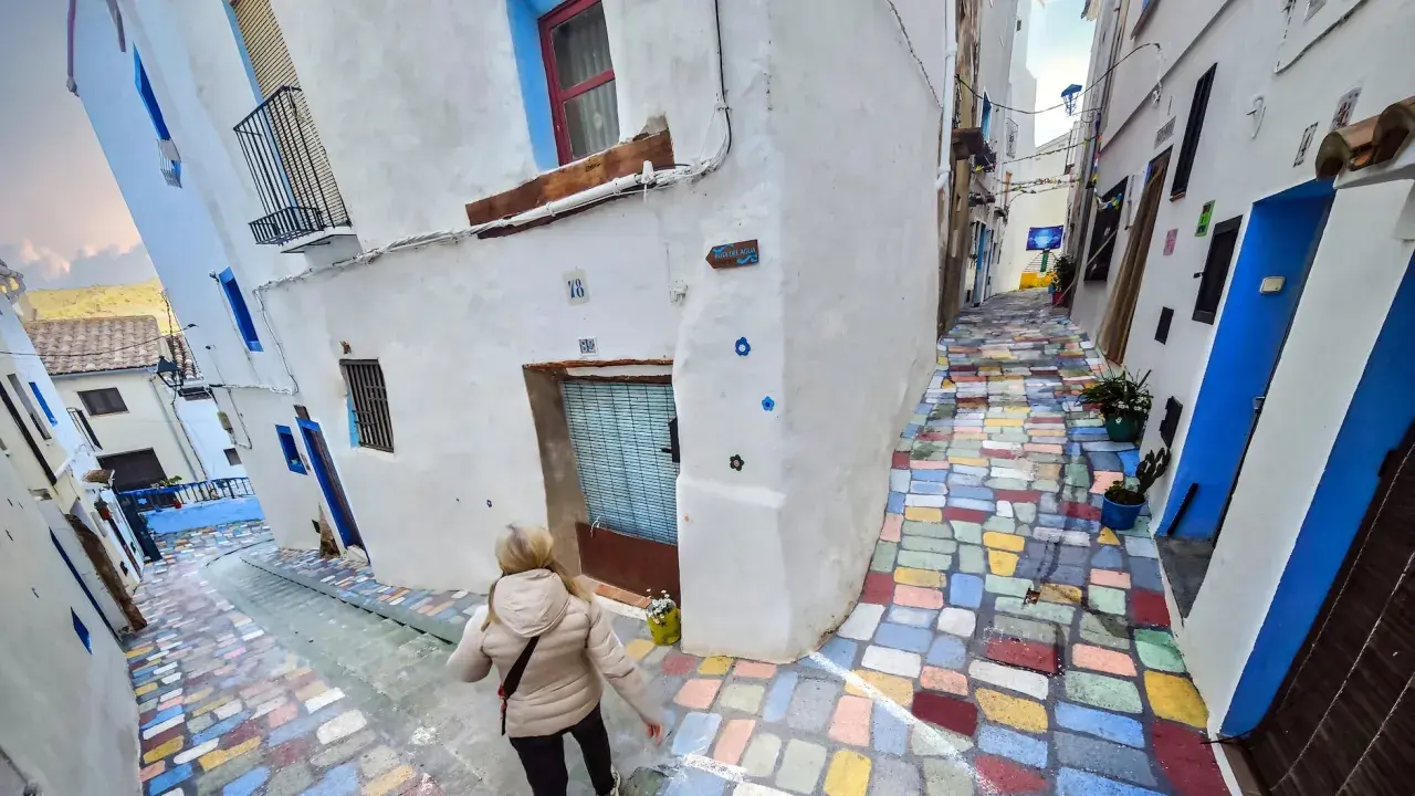 Callejuela de **Chelva pueblo azul**, con escalones de colores vibrantes y casas blancas adornadas con detalles azules.