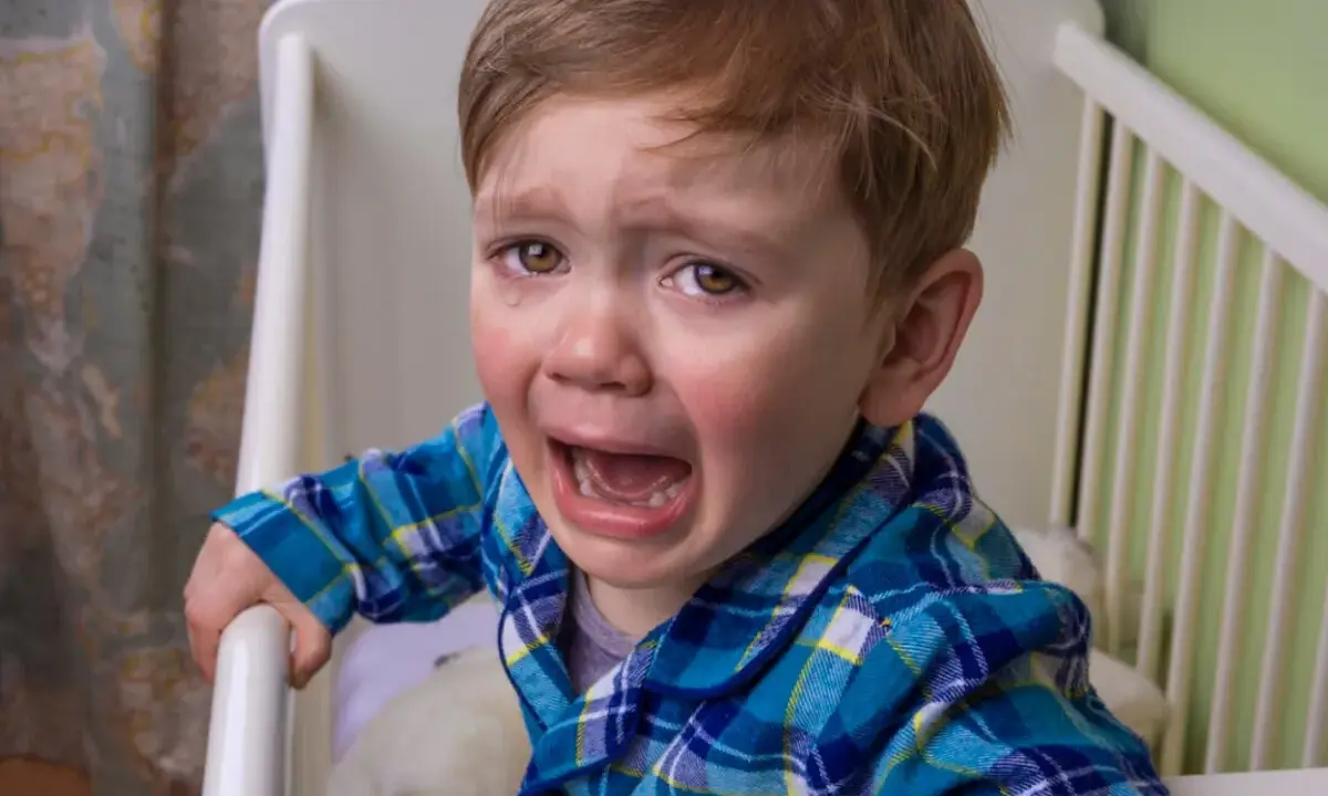 Niño de 10 años llorando en su cuna, se comporta como bebé.