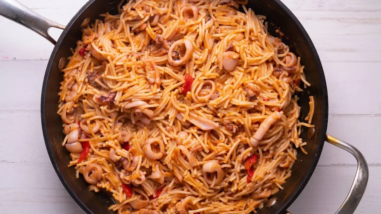 Fideuà de marisco en paellera, con fideos finos, calamares y pimientos rojos. ¡Perfecta para aprender como hacer fideuà!