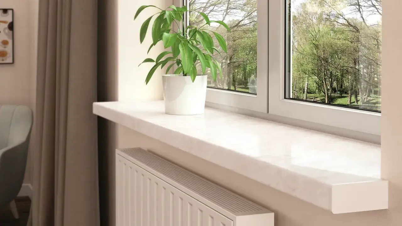 Jasny parapet wewnętrzny z marmurowym wzorem i zieloną rośliną w białej doniczce. Inspiracja, jak dobrać kolor parapetu wewnętrznego.