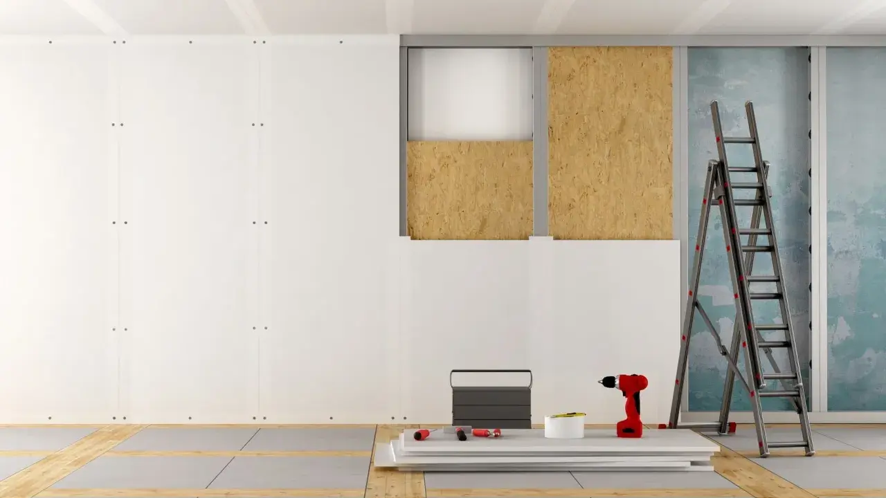 Chantier de pose de plaques de plâtre, avec échelle, perceuse et matériaux. Estimation du prix placo m2.