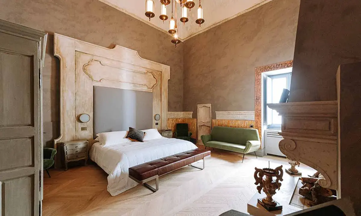 Ett lyxigt sovrum med en stor säng, grön soffa och en imponerande eldstad. Perfekt hotell inredning inspiration för ett elegant hem.
