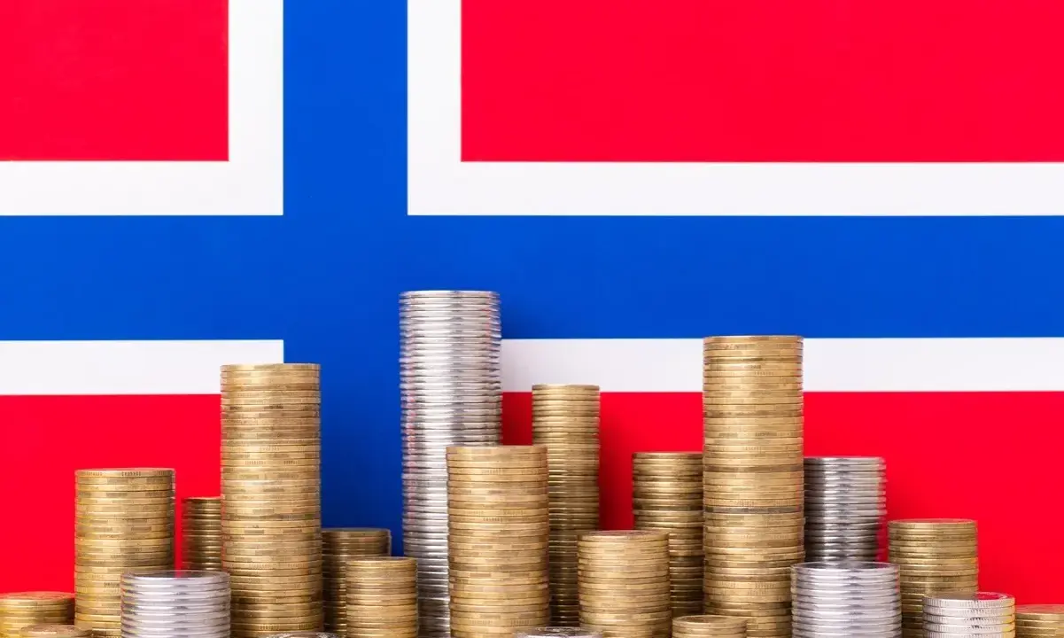 Stosy monet na tle flagi Norwegii symbolizują oszczędności i przyszłość, być może związane z wiekiem emerytalnym w Norwegii.