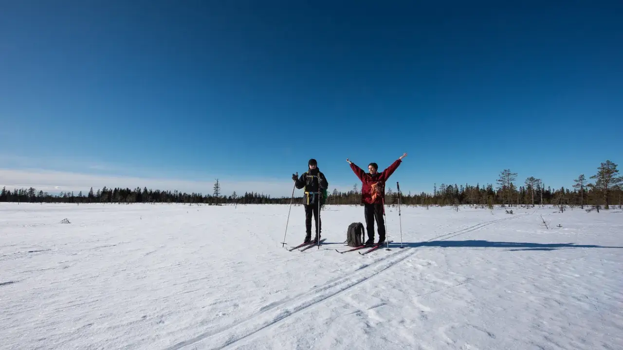 Två skidåkare njuter av en solig dag i Koppången naturreservat.