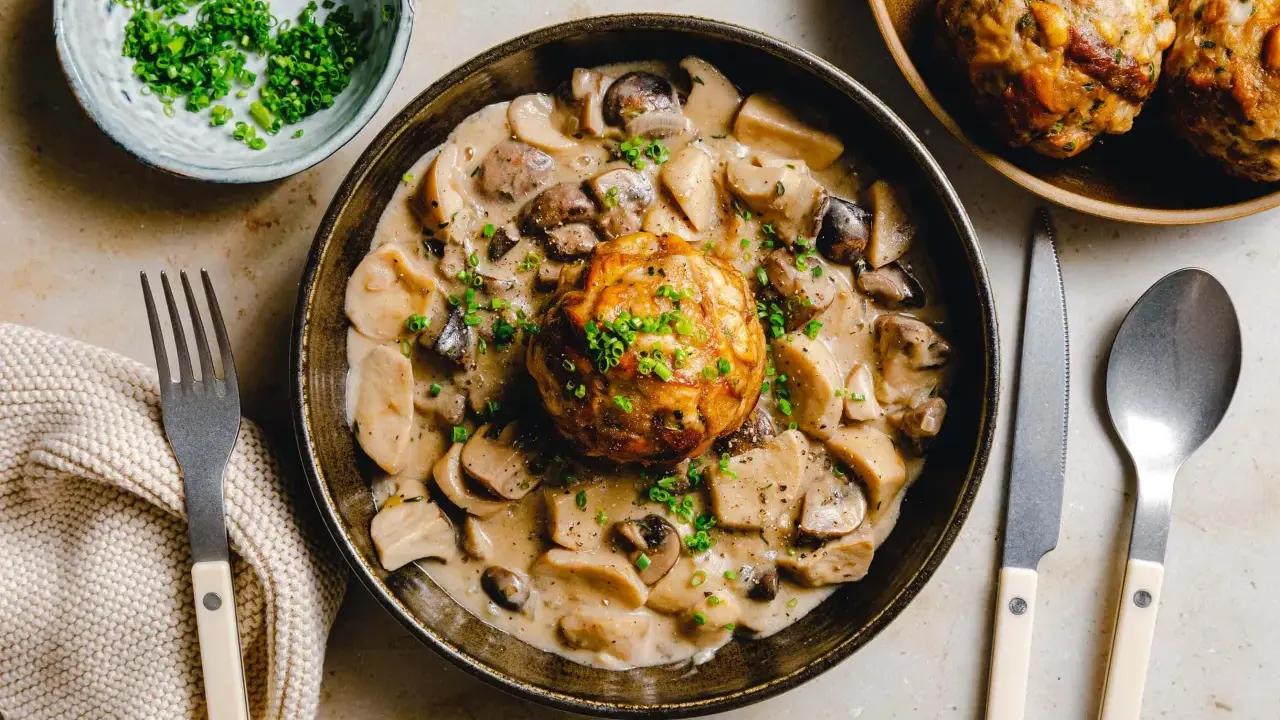 Herzhaftes Gericht: Ein Knödel in cremiger Pilzrahmsoße, garniert mit Schnittlauch. Perfekt, was passt zu Brezenknödel!