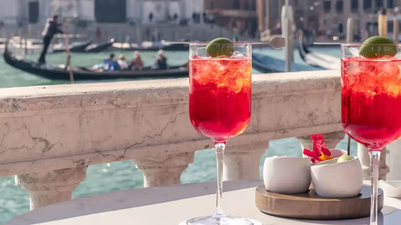Deux Spritz vénitiens rafraîchissants sur une terrasse avec vue sur les canaux de Venise et les gondoles.