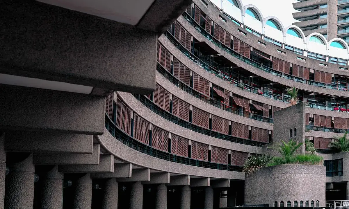 Edifici curvi in cemento con persiane in legno al Barbican Centre. Un'architettura iconica che si staglia nel cielo.